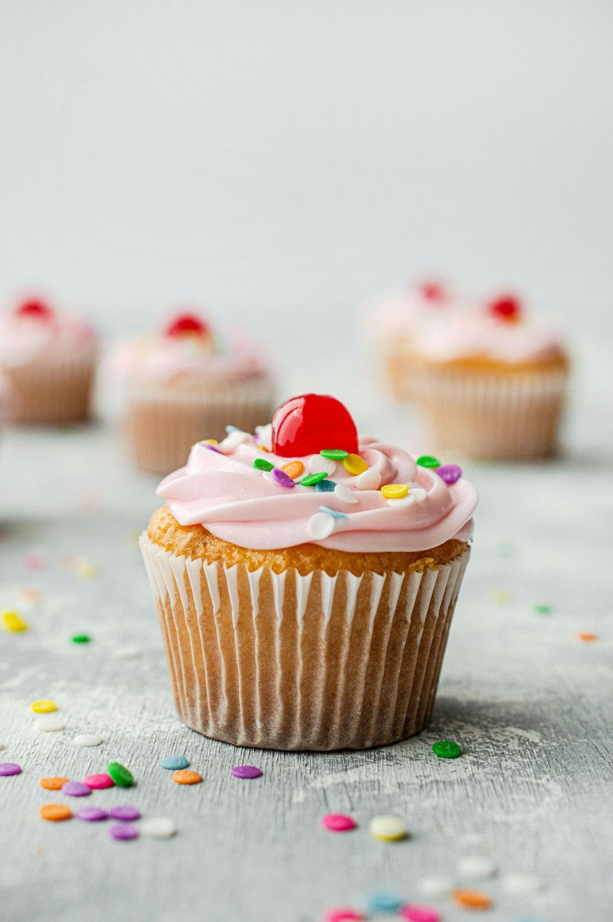 Un cupcake con glassa rosa, codette colorate e una ciliegina sopra