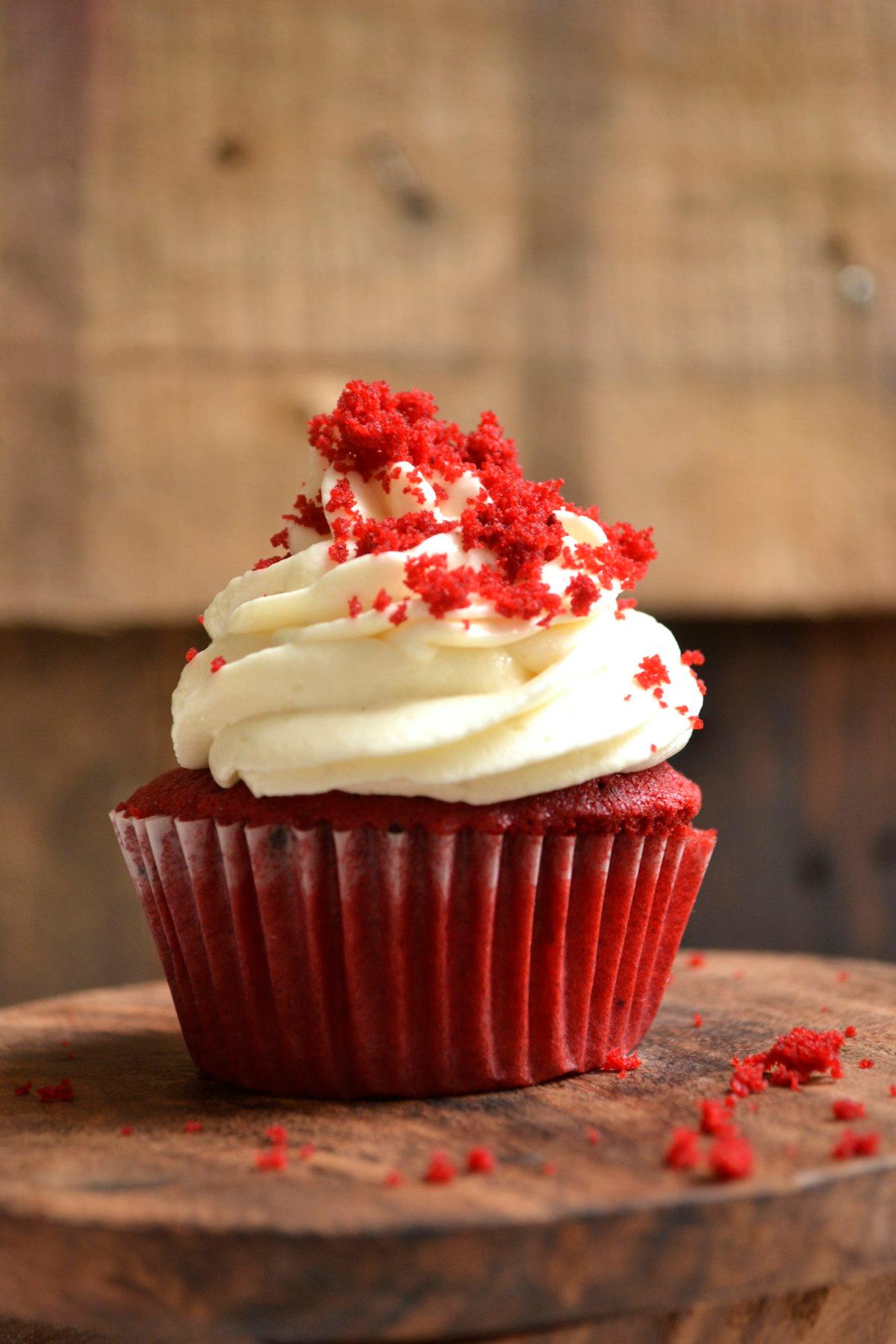Un cupcake red velvet con frosting al formaggio cremoso su un'alzata di legno