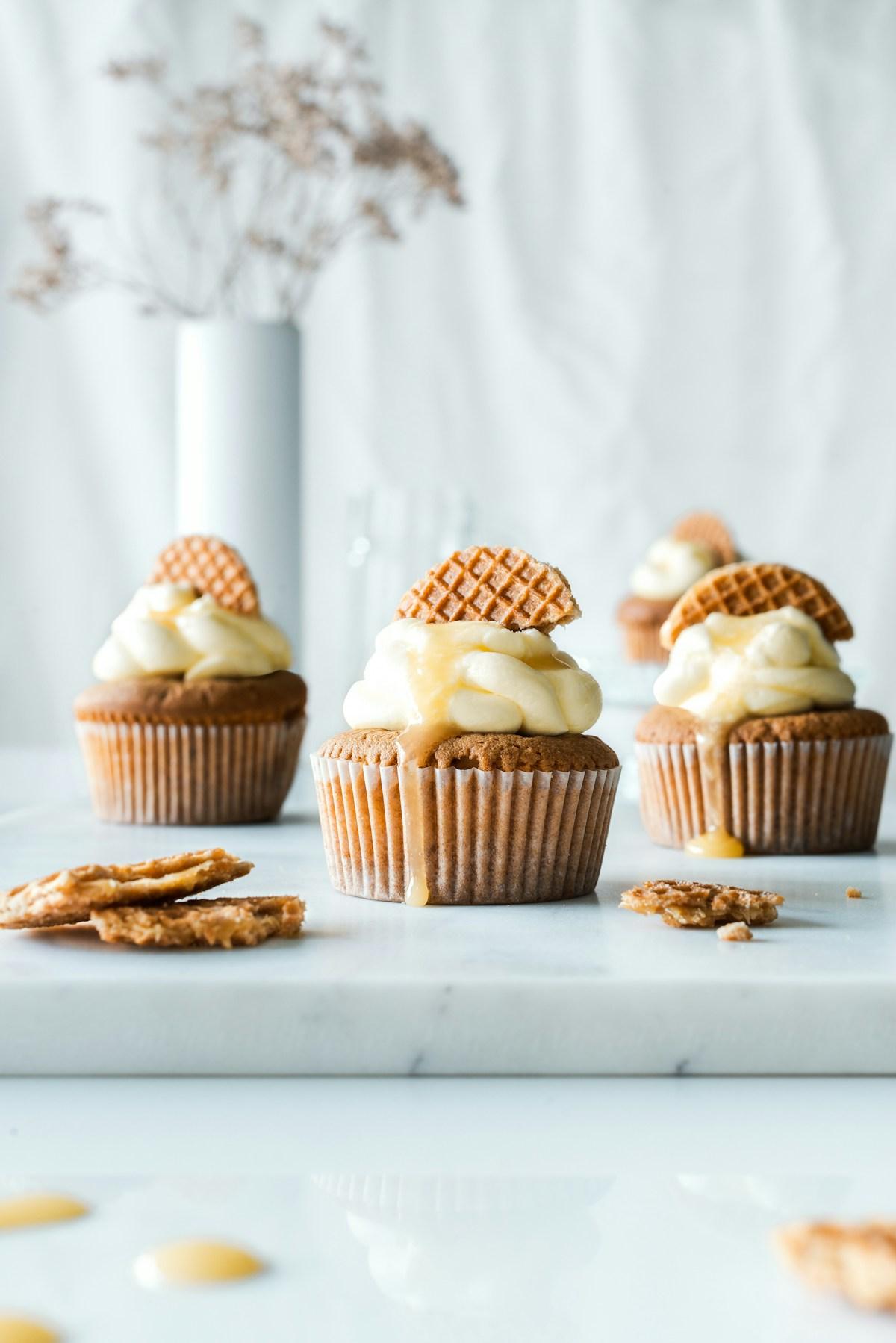 Spiced cupcakes with cream frosting, a waffle cookie, and a honey drizzle on a marble board