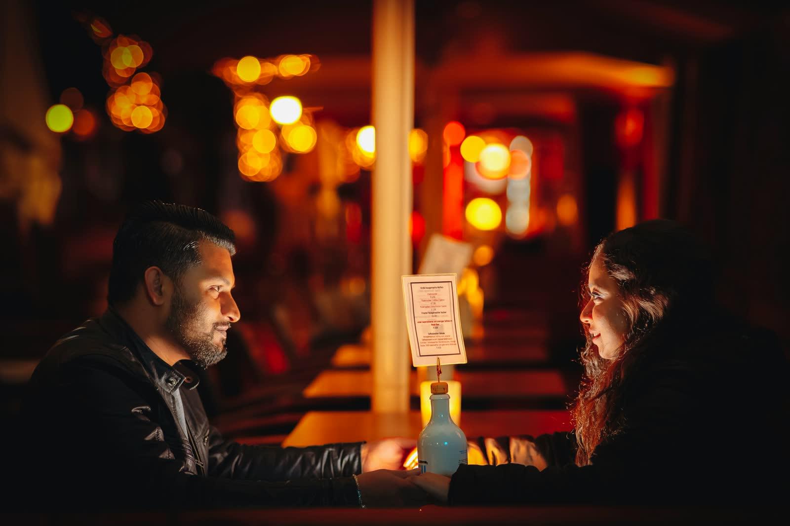 Una pareja tomada de la mano por la noche en una mesa de restaurante iluminada con velas